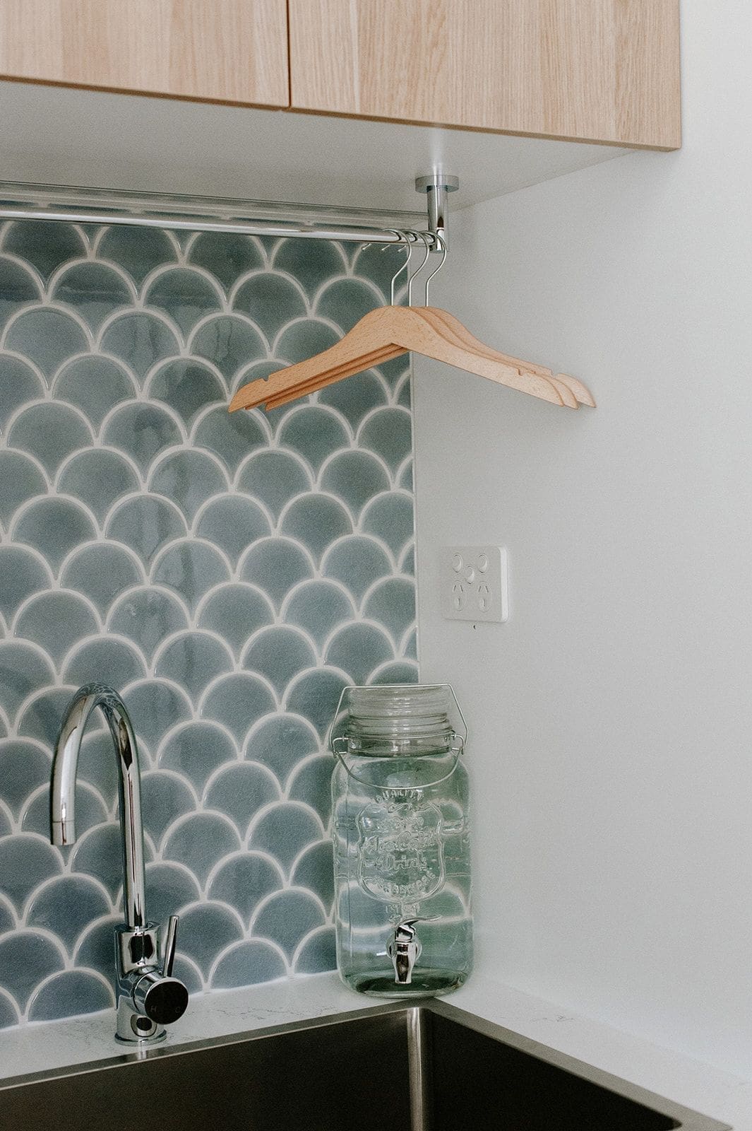 Under-stair laundry with fishscale tile and hanging space