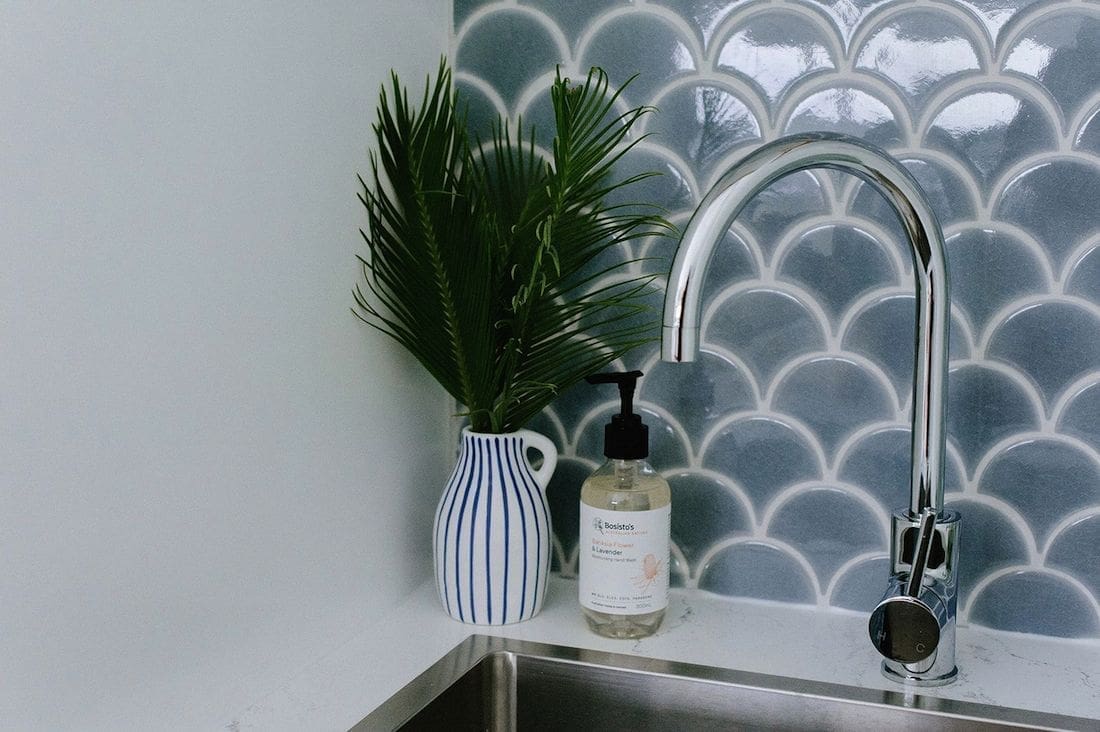 Under-stair laundry with fishscale tile and chrome tap
