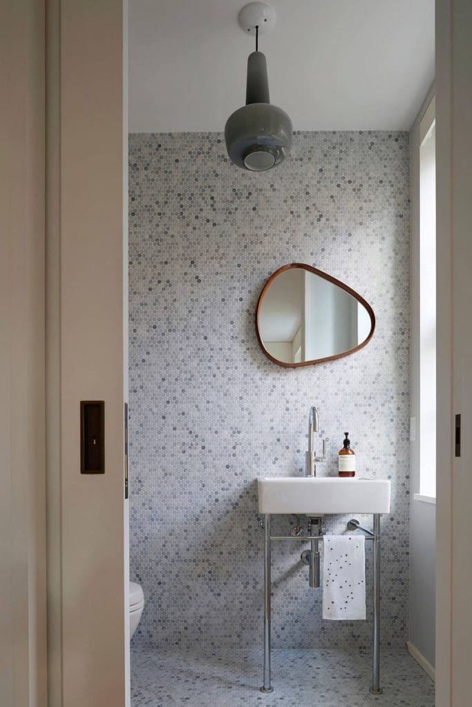 Organic shaped mirror in penny round bathroom