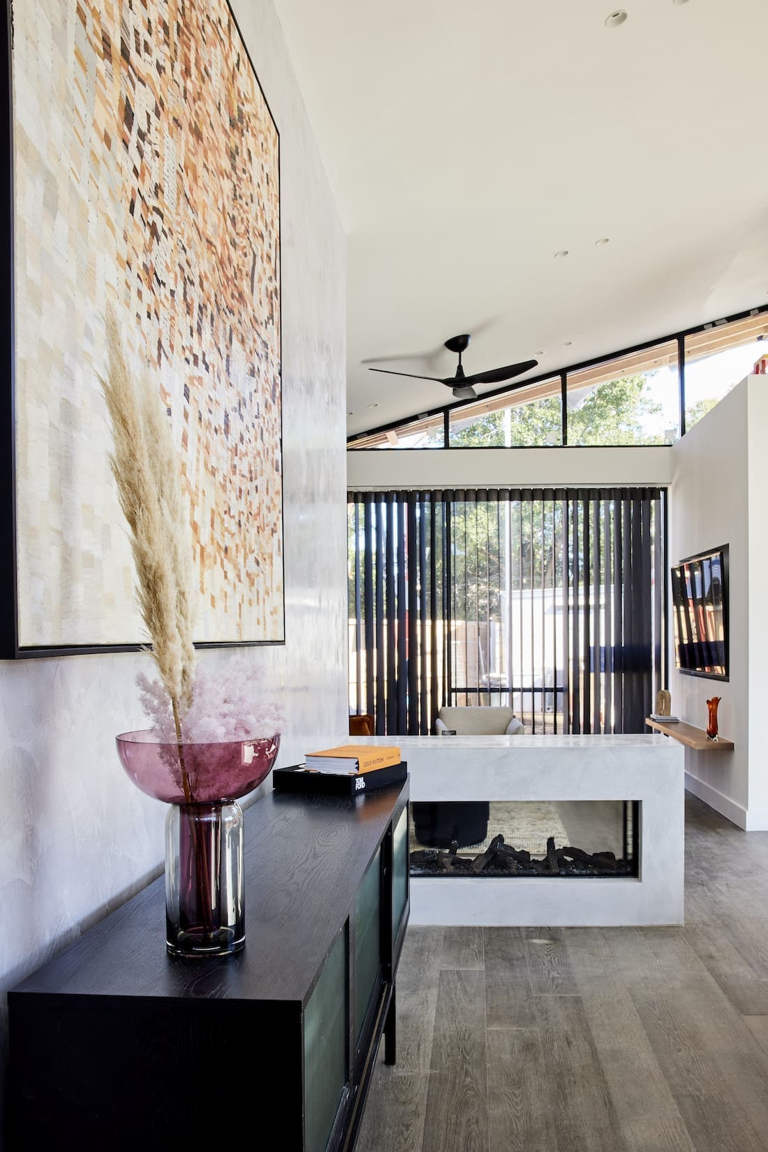 Low-walled glass fireplace with black sheer curtains