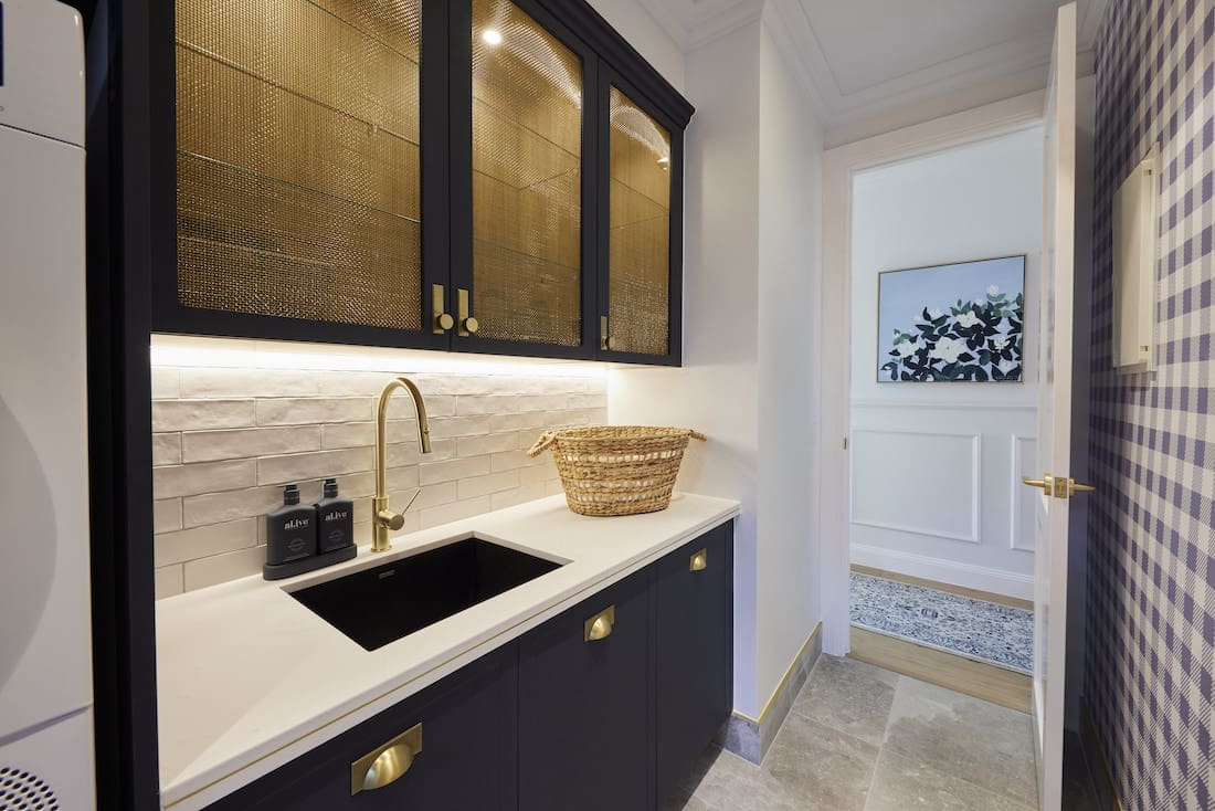 Laundry with navy cabinetry and brass inset