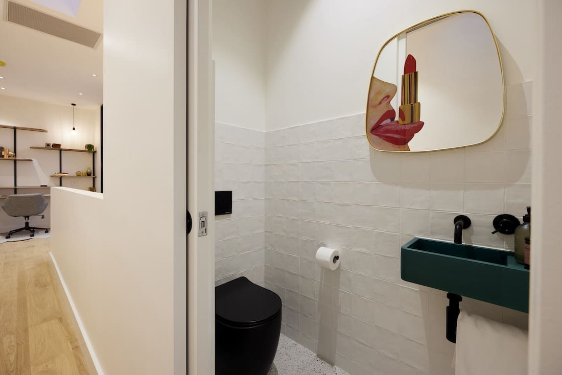 Black toilet, green basin and mirror with mouth and lipstick