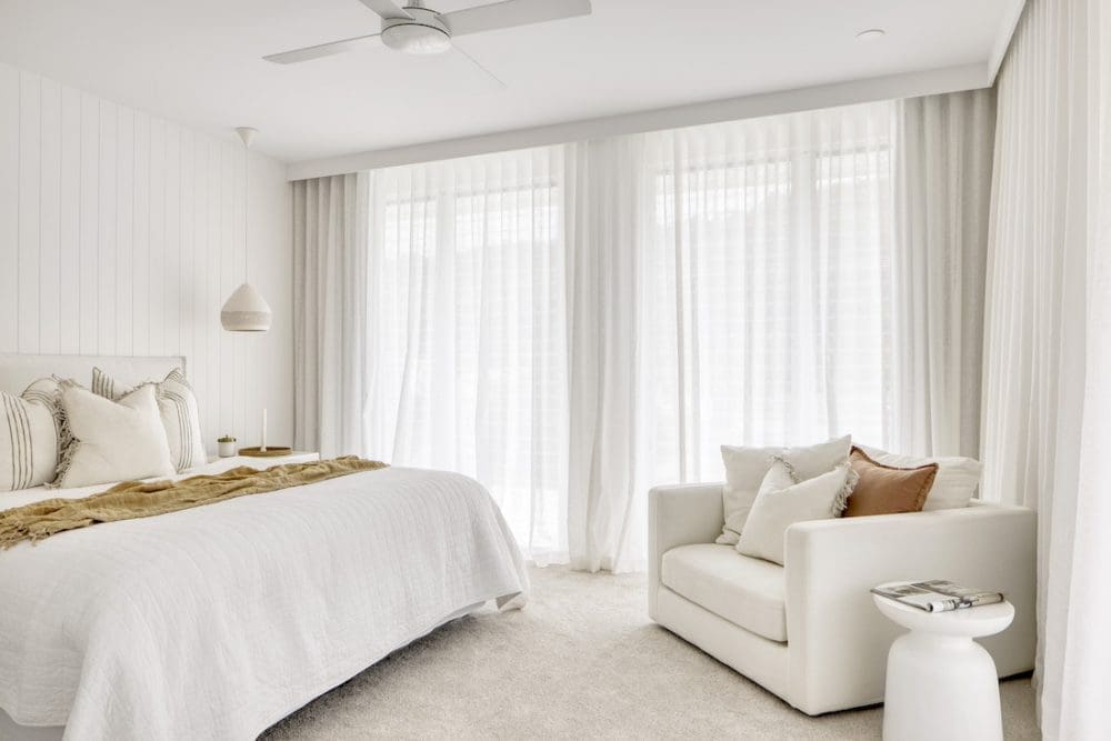 White master bedroom with occasional chair at Tawarri house