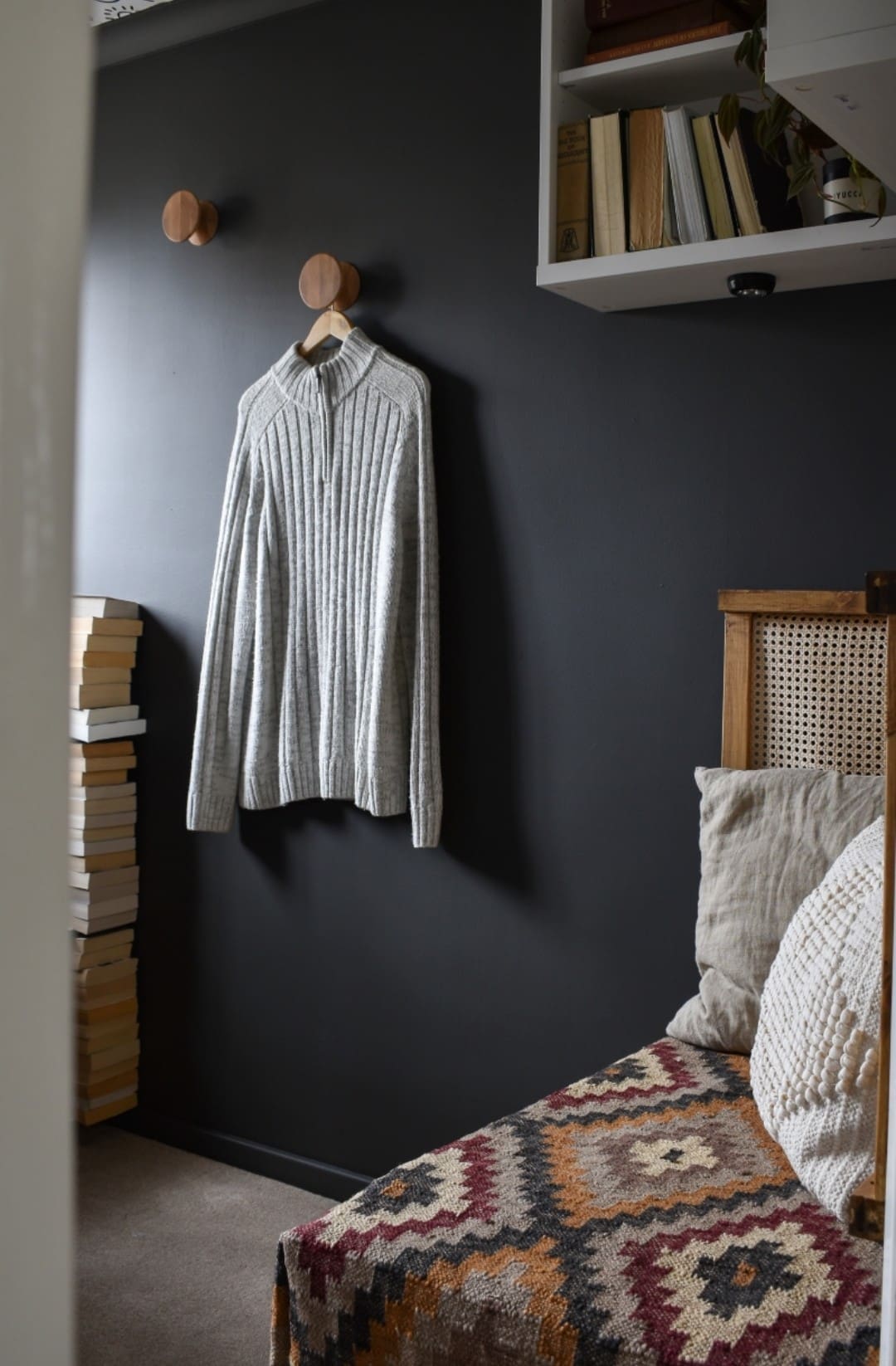 Dark wall room with patterned seating and timber wall hooks