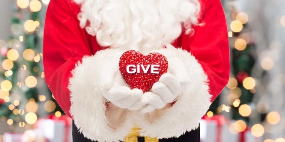 Santa holding a red heart that says GIVE