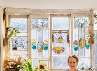 Ivy De Bruijn, the artist behind Ivy's Glass Cottage in front of stained glass art