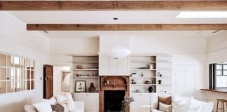Living room with timber fireplace and overhead wooden beams in Rocklee House