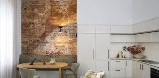 Exposed brick dining nook opening into living and kitchen in Tribeca Brewery apartment by The Stylesmiths