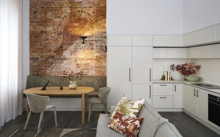 Exposed brick dining nook opening into living and kitchen in Tribeca Brewery apartment by The Stylesmiths