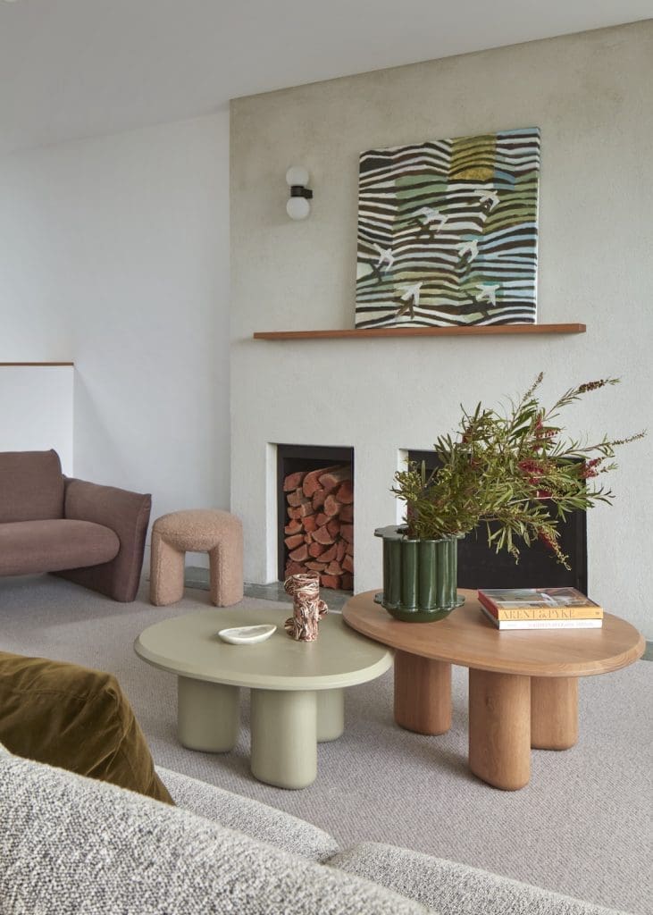Living room with 2 coffee tables and artwork above fireplace