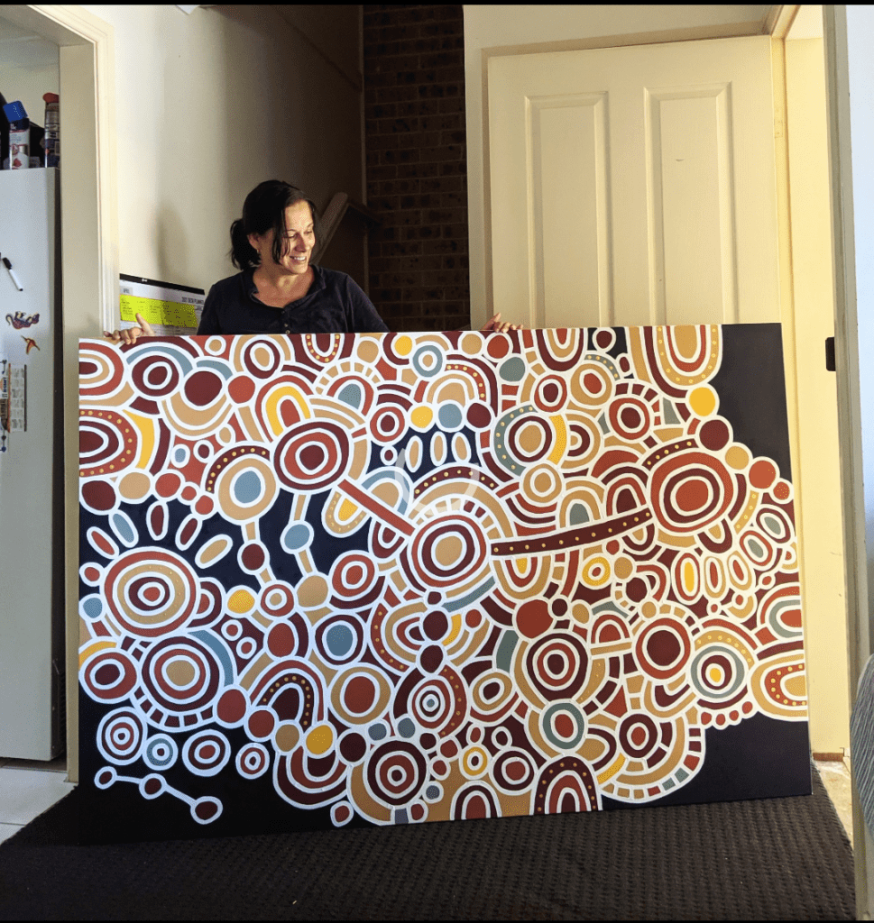 Karen Lee Mungarrja holding large scale Indigenous art piece