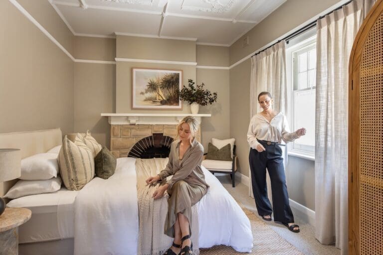 Alisa and Lysandra in bedroom of their coastal heritage Tudor AirBnB