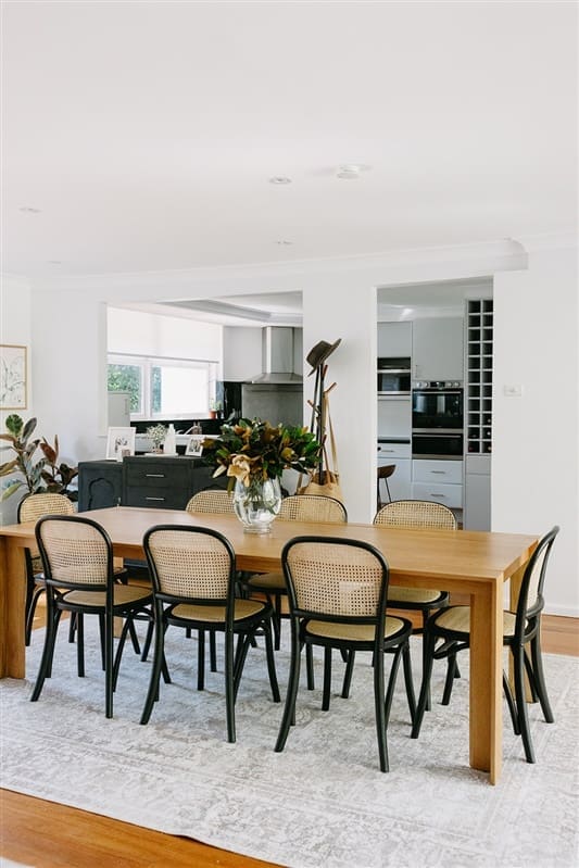Long dining table with black and rattan dining chairs