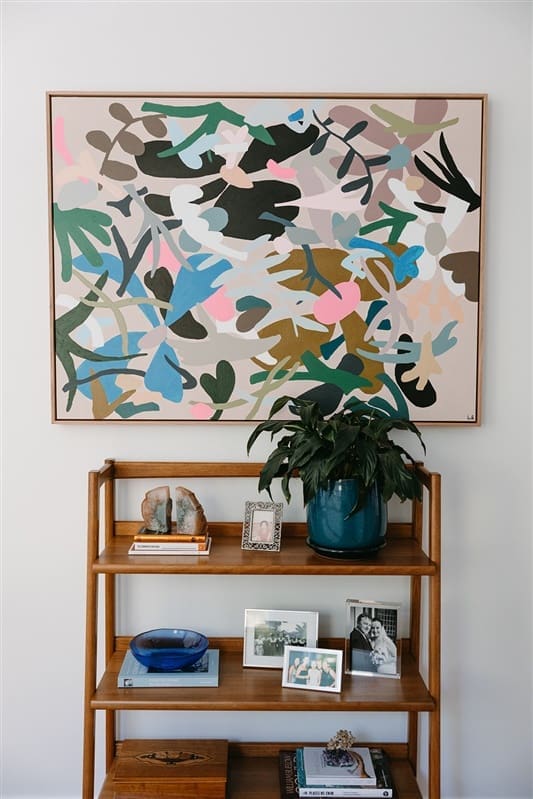 Colourful abstract art above small shelving unit in hallway