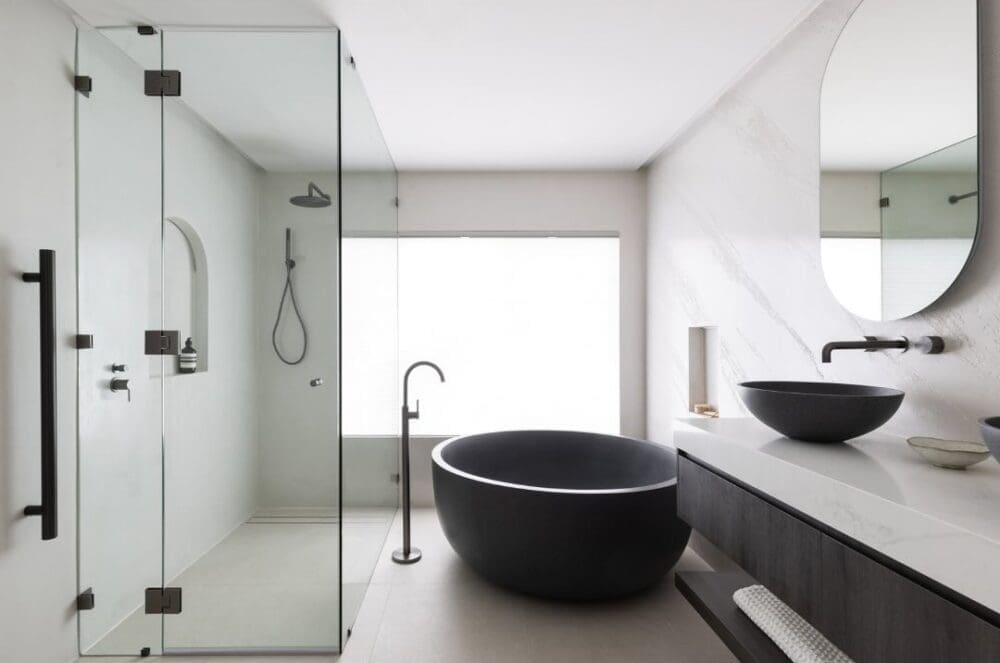 Gooseneck tap next to black round bath