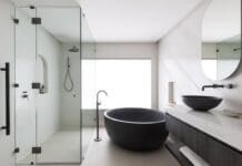 Gooseneck tap next to black round bath