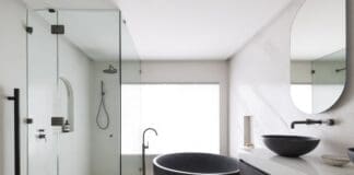 Gooseneck tap next to black round bath