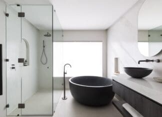 Gooseneck tap next to black round bath