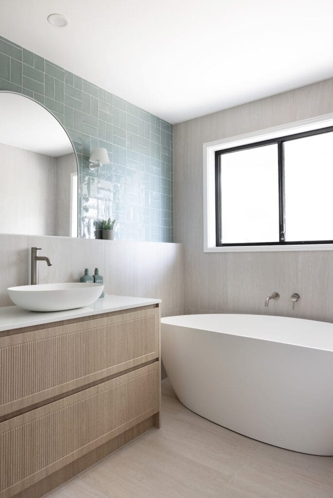 Large curved bath in modern bathroom with blue wall tiles