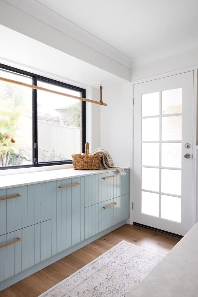 Laundry with blue cabinetry and hanging rail