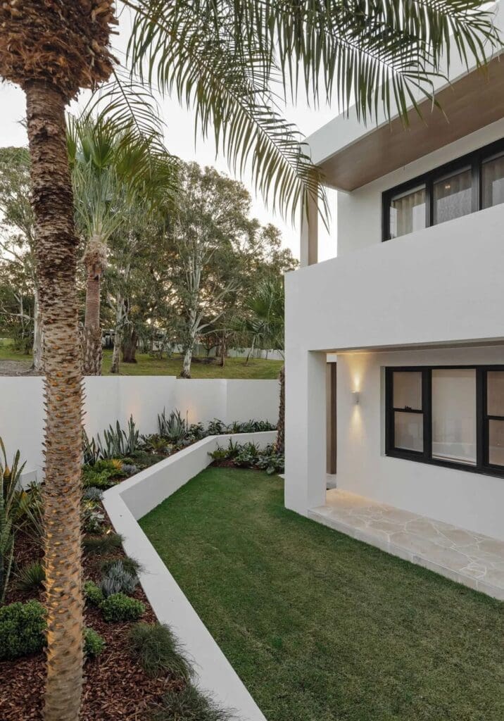 Gardens with large palm trees at front of The Stables Burraneer House