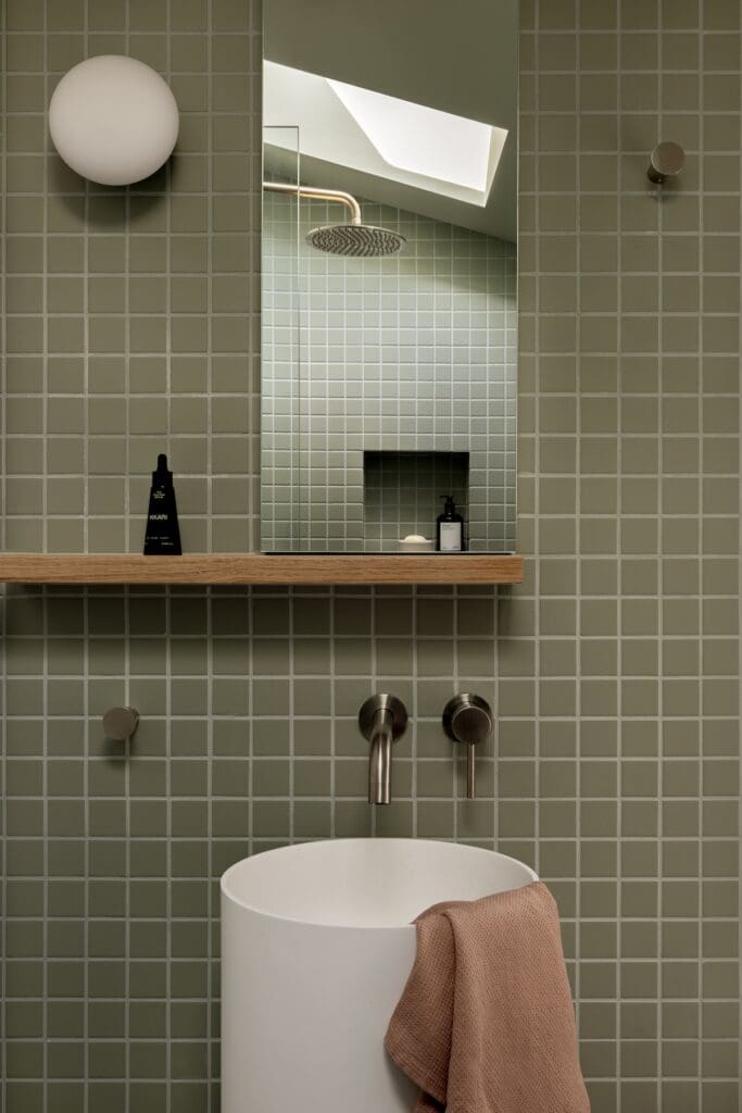 White pedestal basin in green grid tile bathroom
