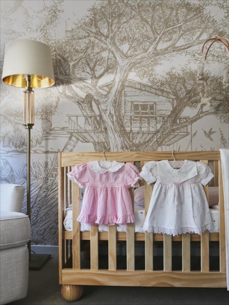 Vintage dresses hanging on timber cot in nursery