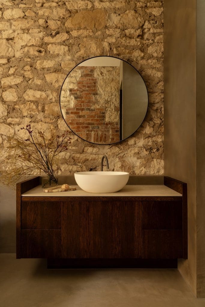 Exposed limestone brick wall in bathroom at Coastal Alchemy by The Stylesmiths